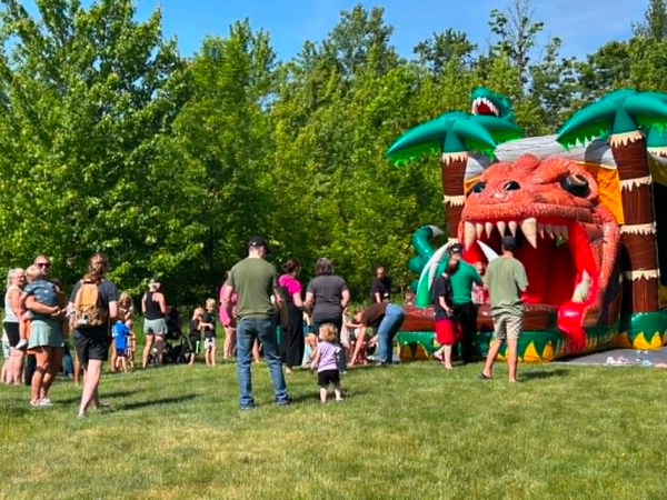A group of people in front of an inflatable dinosaur jumping area